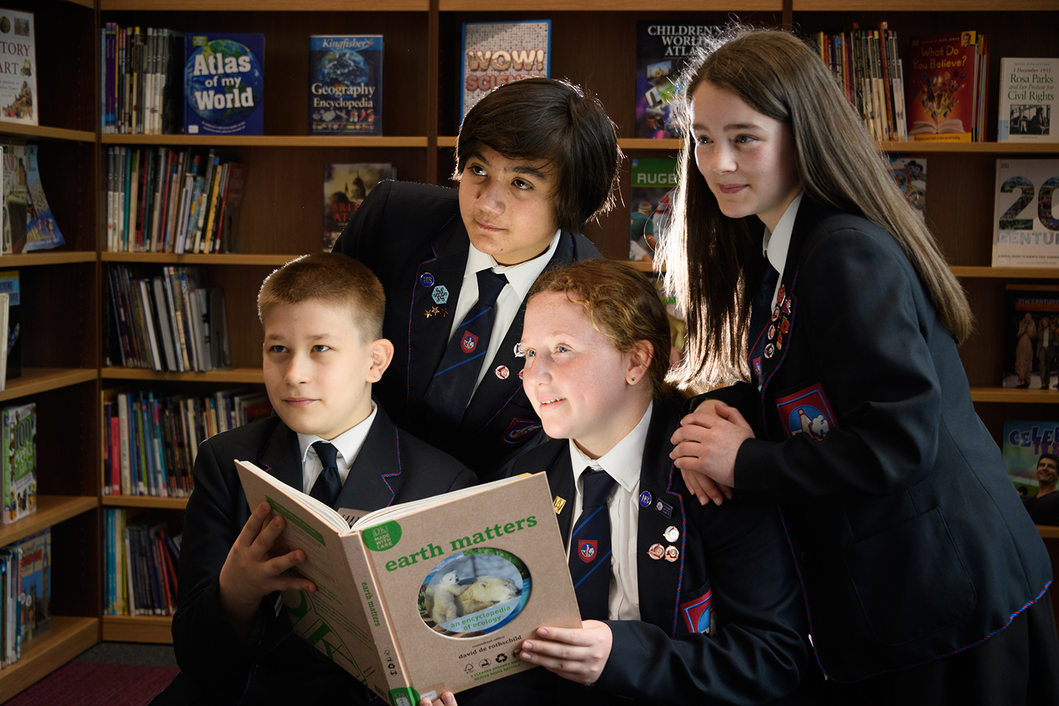 Four students in the library holding a book